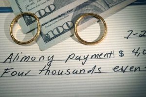 two wedding bands on top off two hundred dollar bills and a check that says alimony payment symbolizing Lake County - Waukegan alimony and spousal support payments 